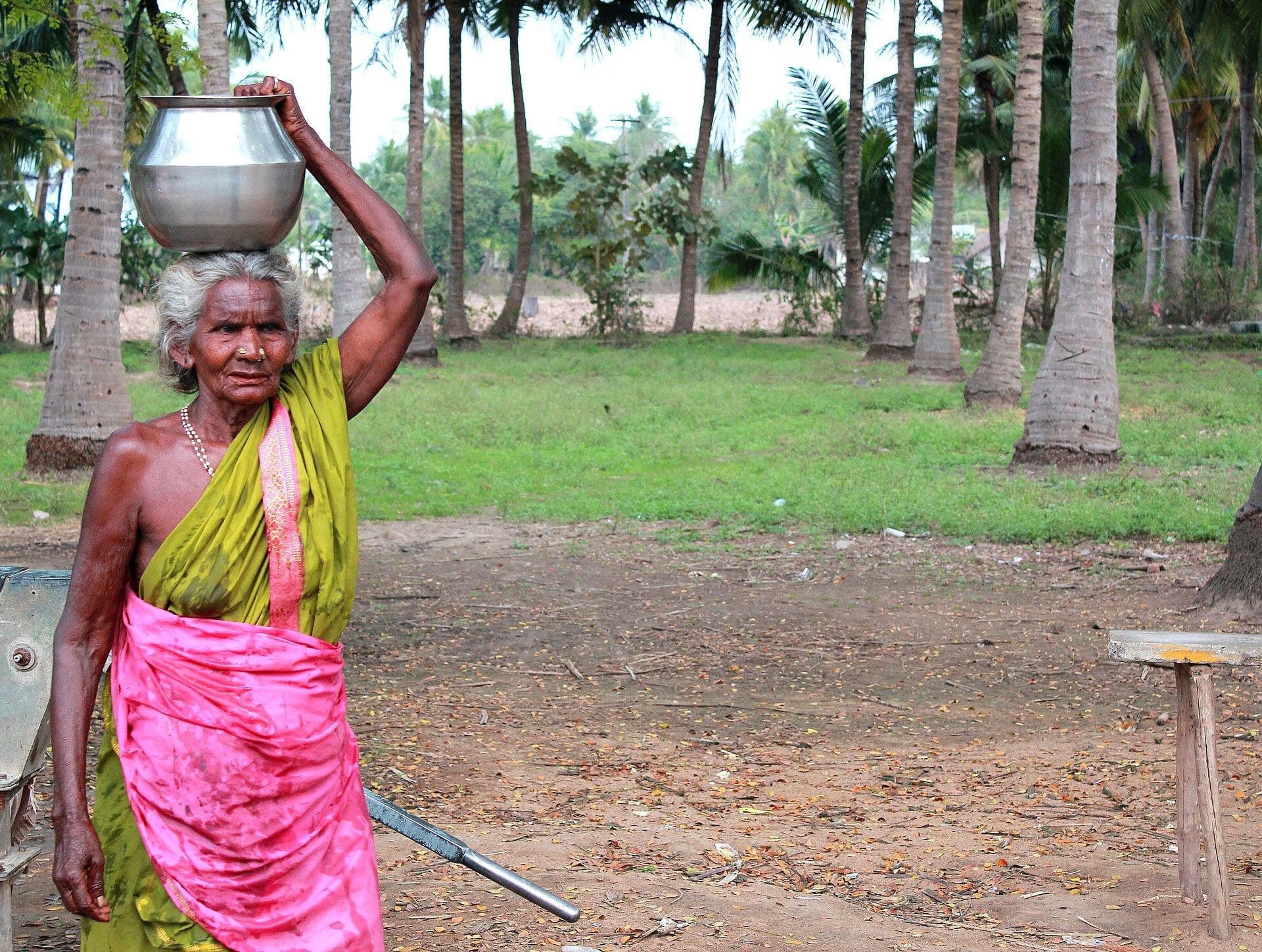 An elderly woman carrying a water pot